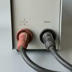 Welder output sockets marked plus and minus, with a cable plugged into each